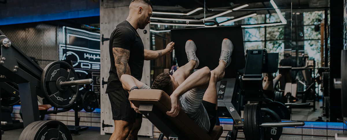 Personal trainer spotting a client on the leg press at King Beats Fitness Glebe